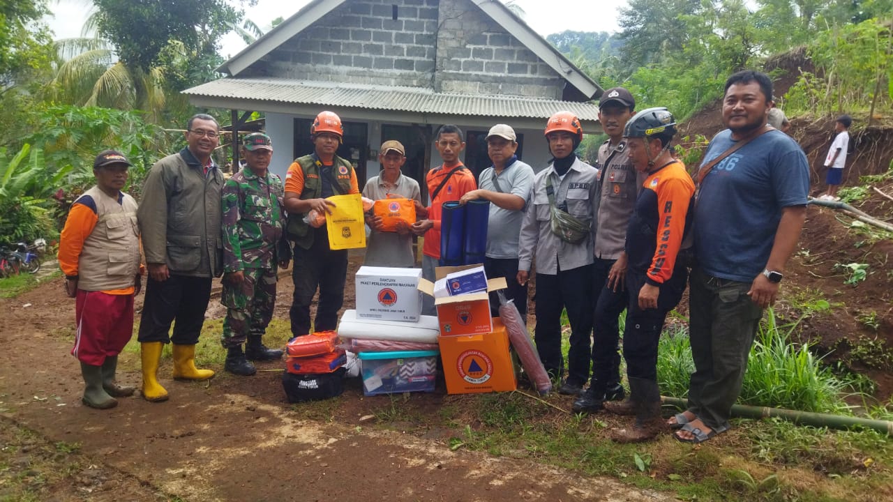 Sejumlah anggota kepolisian dari Polsek Tempursari bersama warga bahu-membahu membersihkan sisa-sisa material longsor yang menimpa rumah Siono di Dusun Tamansari.